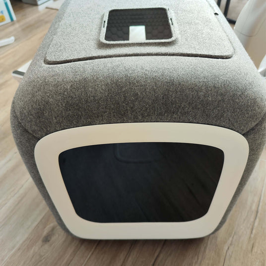 Modern gray pet grooming tool with rounded edges and black entrance opening.